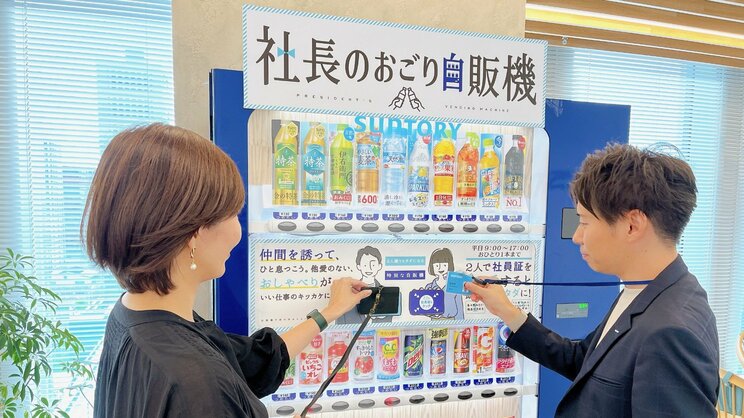 実際に「おごり自販機」を使って購入する様子（写真右が松本さん）