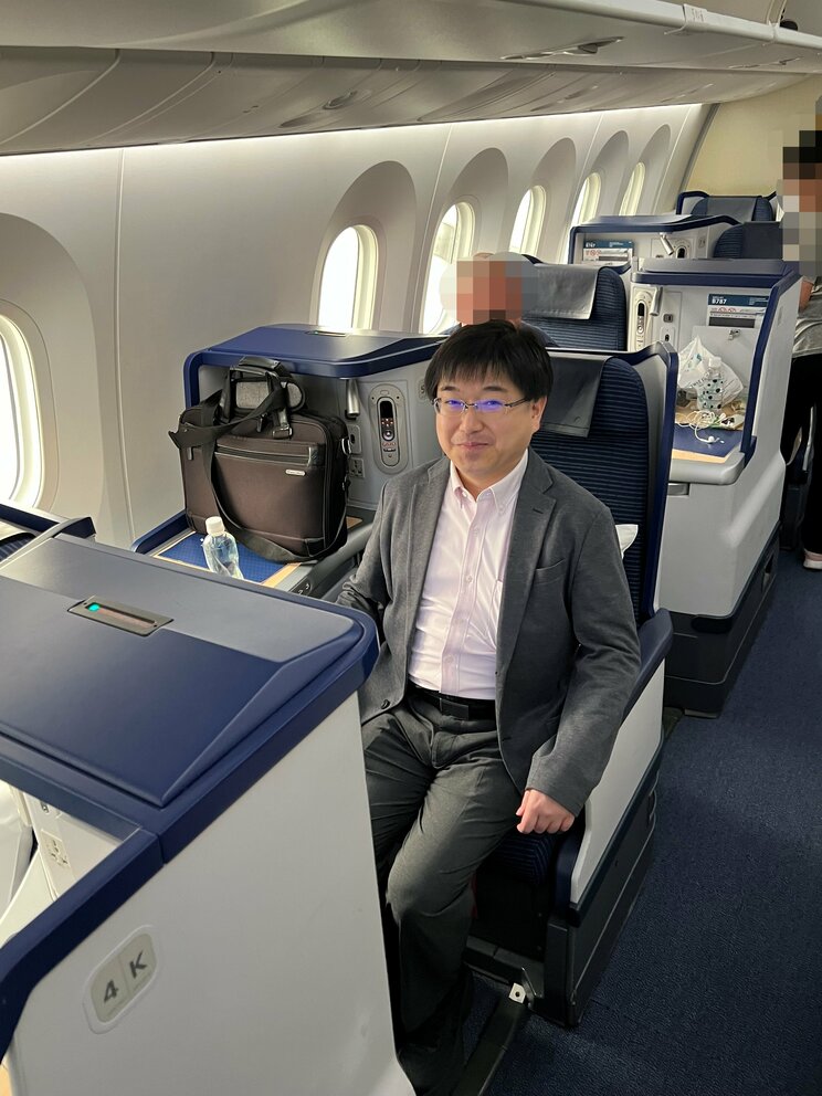 ビジネスクラスに乗る吉崎被告（関係者提供）