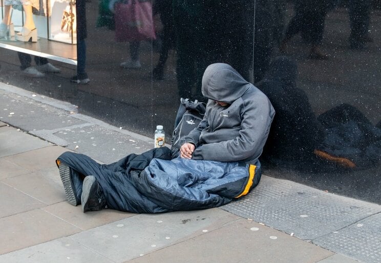 英国マンチェスターのマーケット通りに座っているホームレスの男性
