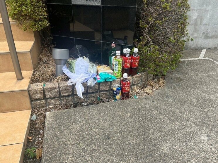 斎藤さんの自宅前には花束や飲み物が置かれていた