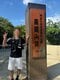 山頂の看板と笑顔で写真を撮る男性