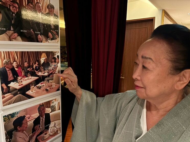 店内に飾られた著名人たちが訪れたときの写真を見つめる水口さん（撮影／集英社オンライン）