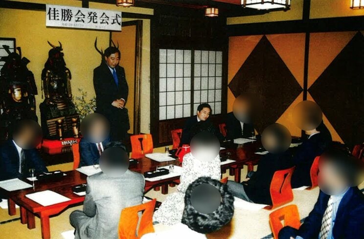野田氏が教団幹部と並んだ場面とする写真