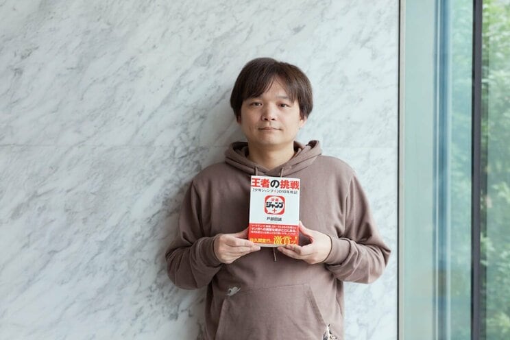 できたばかりの新刊を持つ著者。帯には佐久間宣行（テレビプロデューサー）の熱い推薦文が。