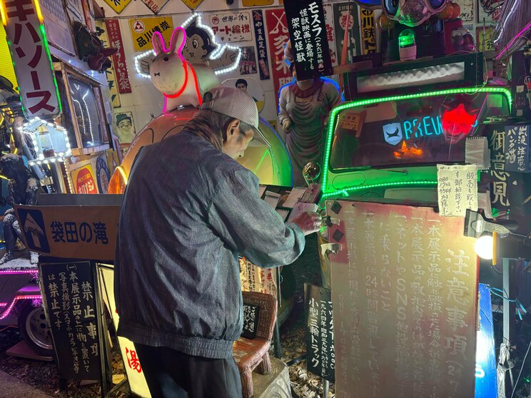 来場者からのメッセージを確認する加藤さん。雨に濡れないよう頻繁に回収しているそう（撮影／集英社オンライン）