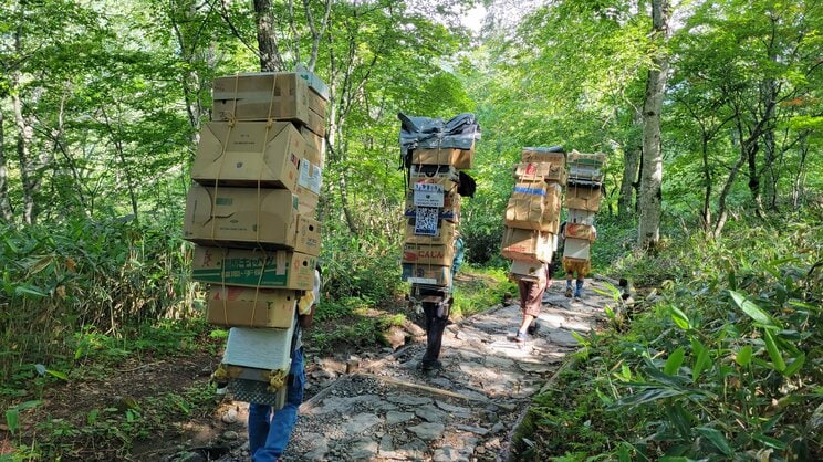 尾瀬の山道を歩く歩荷たち（尾瀬小屋【尾瀬国立公園】提供）