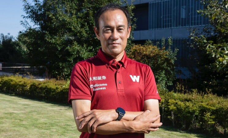 「初めてこれを着て取材を受けます」とスポンサーロゴが入ったチームウエアで取材に応じる花田監督（撮影／高木陽春）