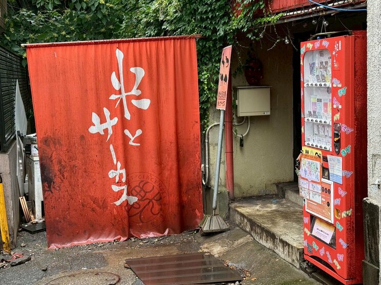 店舗は線路沿いの裏路地にある。右手が自販機（撮影／集英社オンライン）