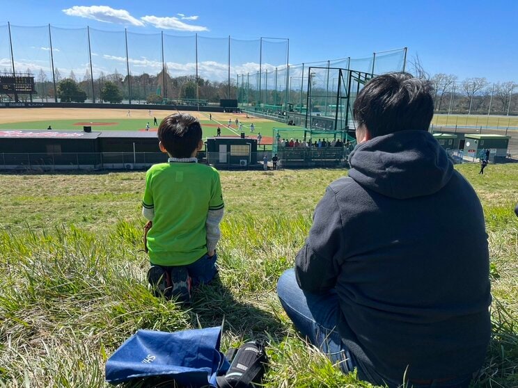 戸田球場外の土手から2軍戦を観戦する親子