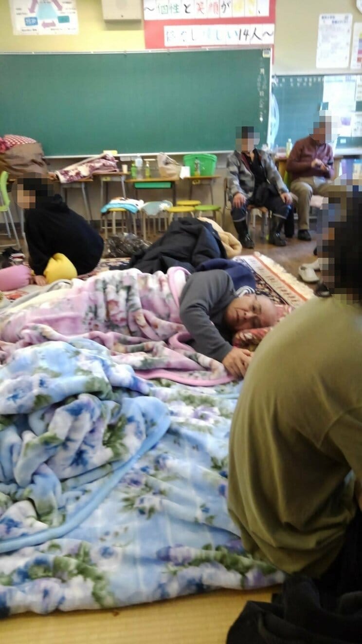 避難所の飯田小学校で集団生活を送る様子。中央で横になっているのが重雄さん（本人提供）