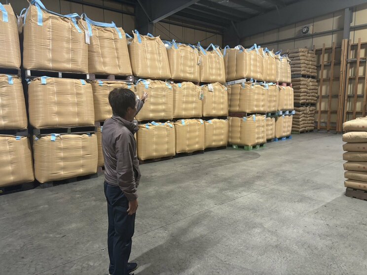 積み上げられた新米を見上げる向後代表（撮影／集英社オンライン）