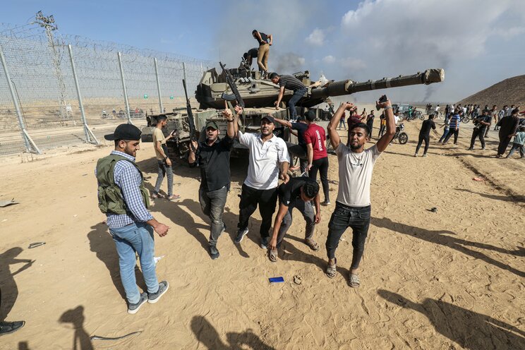 10月7日、パレスチナ自治区にあるイスラエルとの国境フェンスを越えてイスラエルの戦車を制圧するパレスチナ人　写真／DPA・共同通信イメージズ