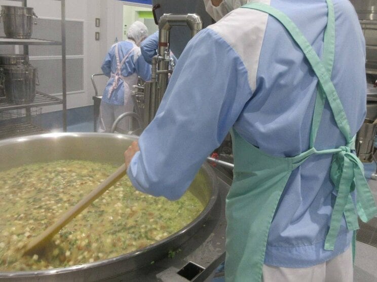 調理員は42〜43度の灼熱のなか、100リットル以上の容量の釜をかき混ぜることも（写真／東洋食品提供）