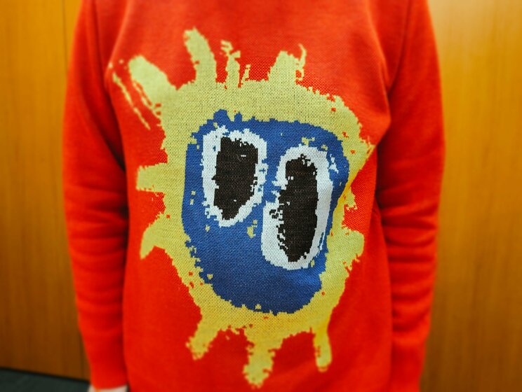 取材にはイギリスのロックバンド、プライマル・スクリームの90年代を代表する名盤『スクリーマデリカ』のジャケがあしらわれたセーターを着て登場した