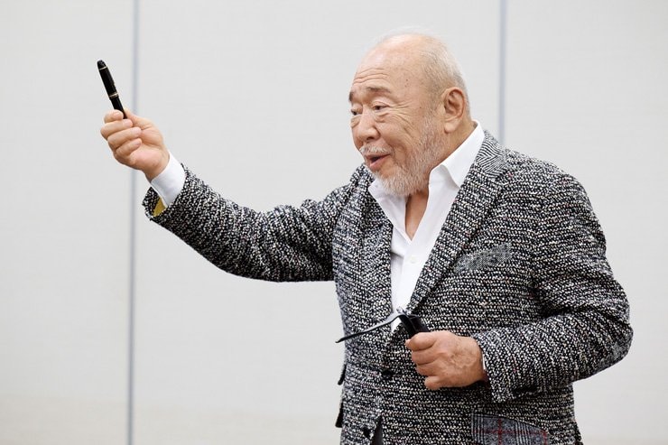 愛用の万年筆を掲げる