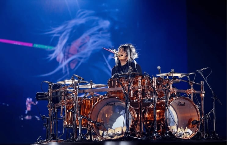 東京ドーム公演でドラムスティックを咥えながらドラムを叩く真矢さん（写真／本人SNSより）