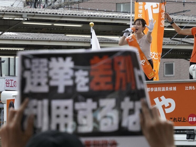 7月13日、成増駅前で演説するさや氏と抗議のプラカード（撮影／集英社オンライン）