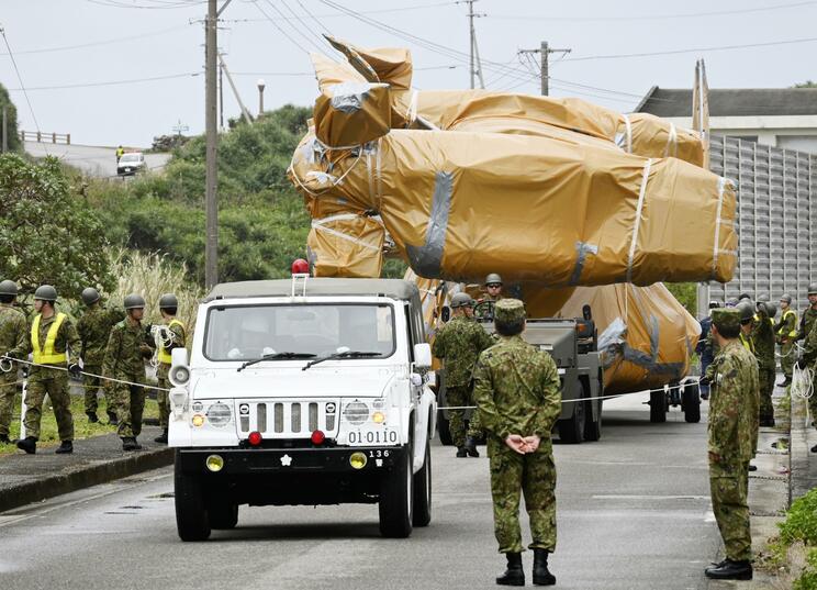 シートにくるまれた輸送中の事故機（写真／共同通信）