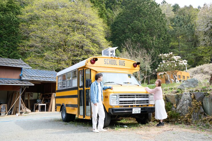 スクールバスの前で談笑する2人（写真／集英社オンライン）