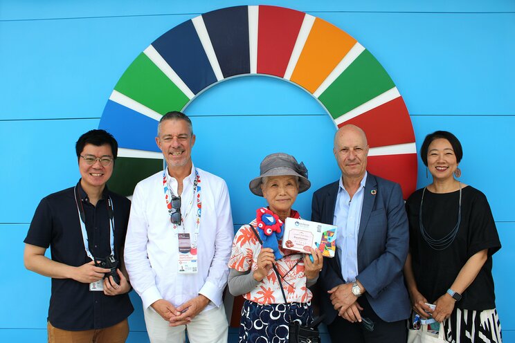 「最も印象に残ったパビリオン」として挙げた「国連館」のスタッフらと写真を撮る山田さん 