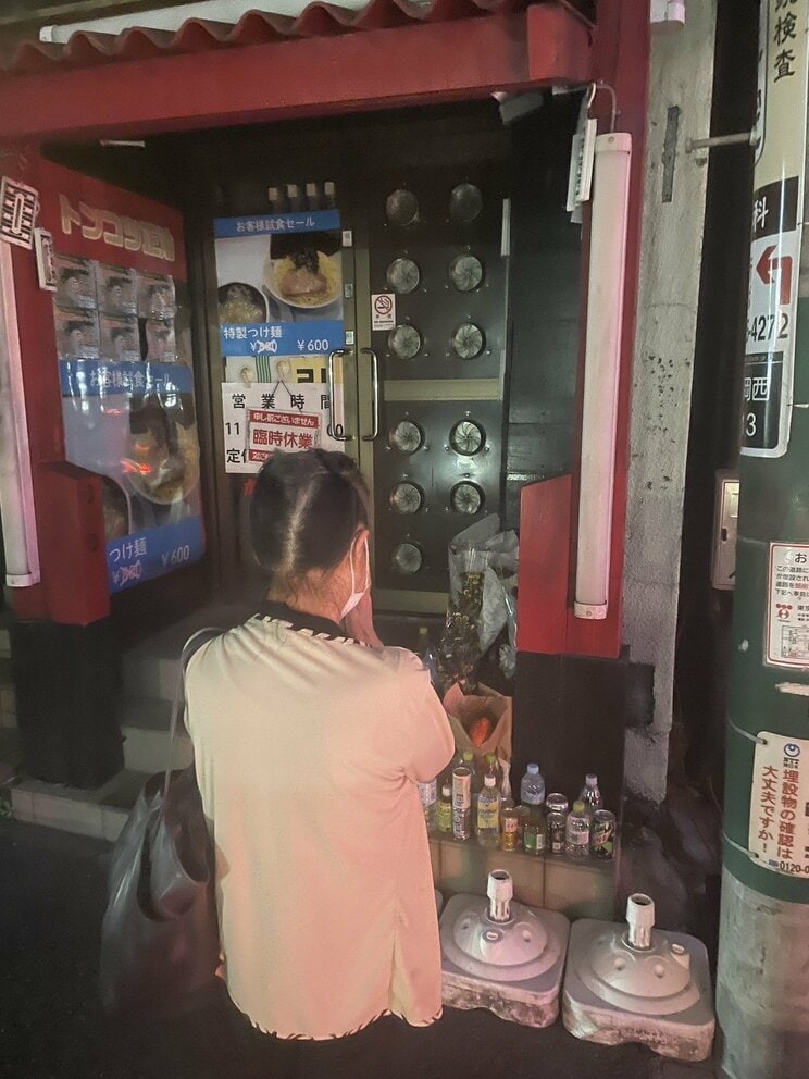 殺害現場となったラーメン店前で手を合わせる女性（撮影／集英社オンライン）