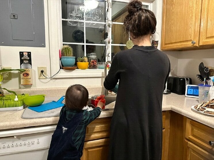 お子さんと家事をする妻（本人提供）