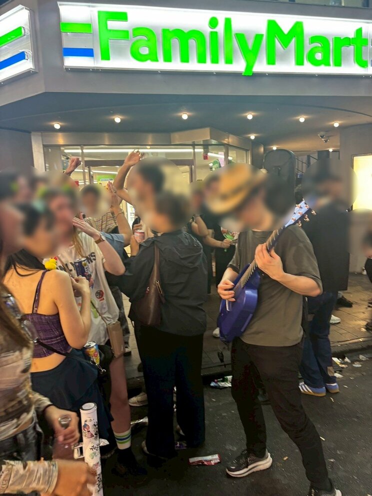 ギター型のスピーカーから大音量の音楽を流す外国人（撮影／集英社オンライン）